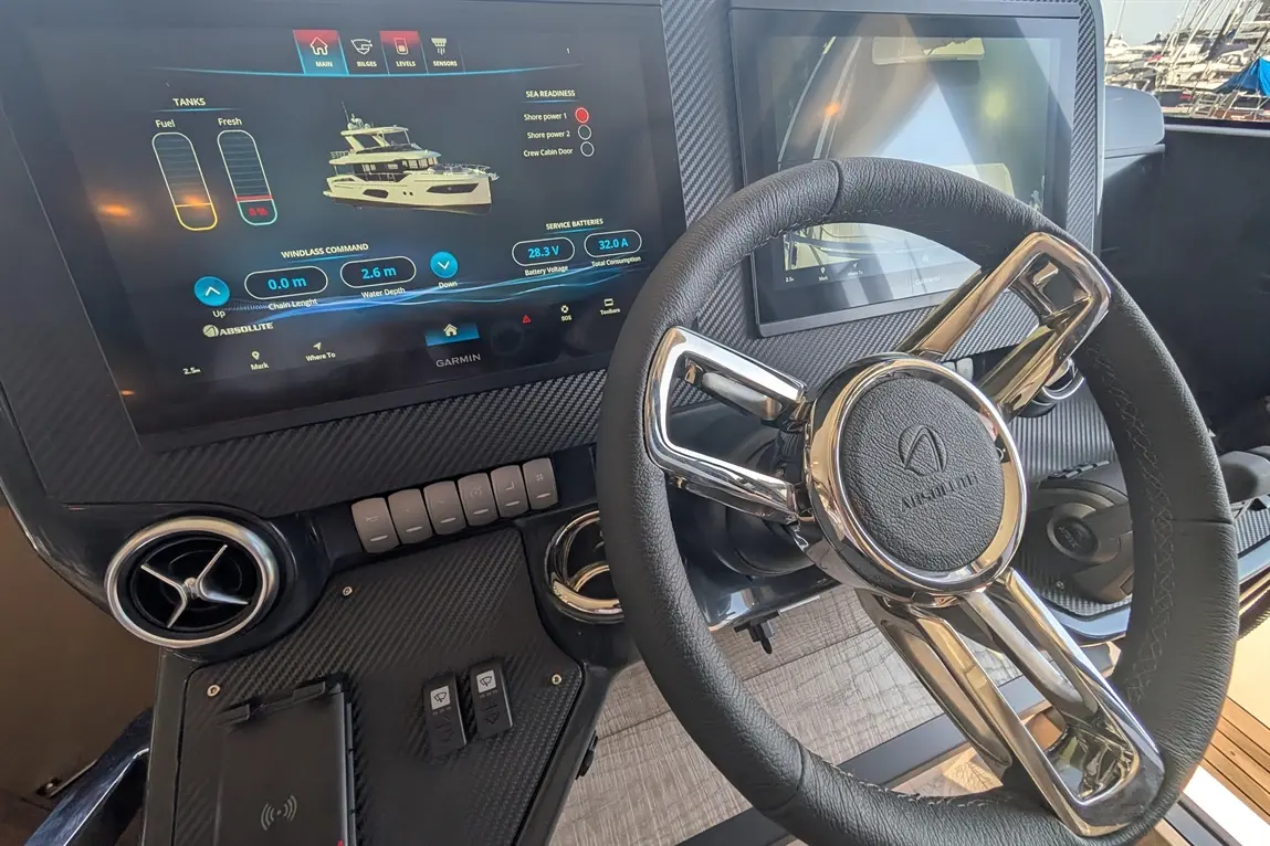 Modern boat dashboard featuring Garmin screens displaying battery status, tank levels, and navigation controls.